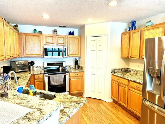 a kitchen with stainless steel appliances kitchen island granite countertop a sink stove and refrigerator
