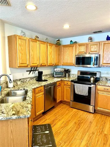 a kitchen with granite countertop a stove a sink and a microwave