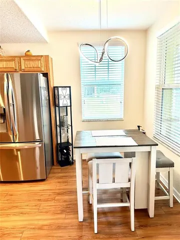 a kitchen with a refrigerator a stove and a dining table with wooden floor