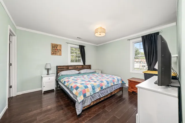 a bedroom with a bed a flat screen tv and a window