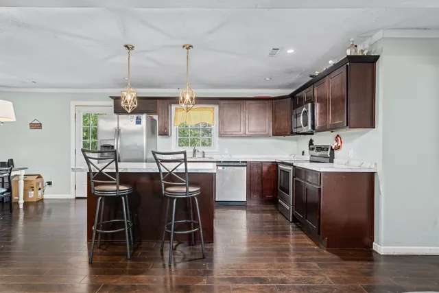 a kitchen with stainless steel appliances granite countertop a stove top oven a refrigerator a sink and a center island