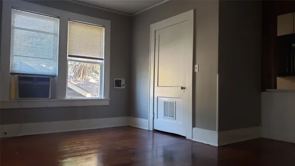 a view of an empty room with wooden floor and a window