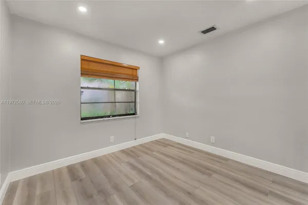 a view of empty room with wooden floor and fan