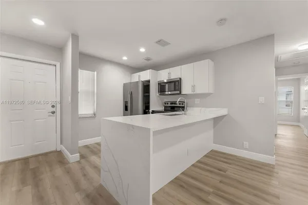 a kitchen with stainless steel appliances a white refrigerator cabinets and wooden floor