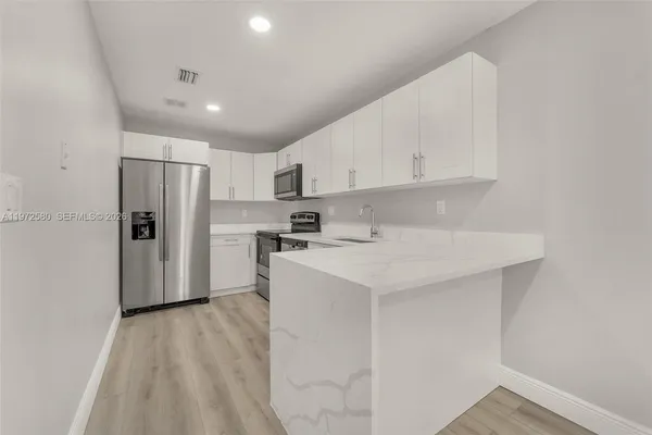 a kitchen with a sink a refrigerator and white cabinets