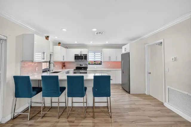 a kitchen with stainless steel appliances kitchen island granite countertop a table chairs and a refrigerator