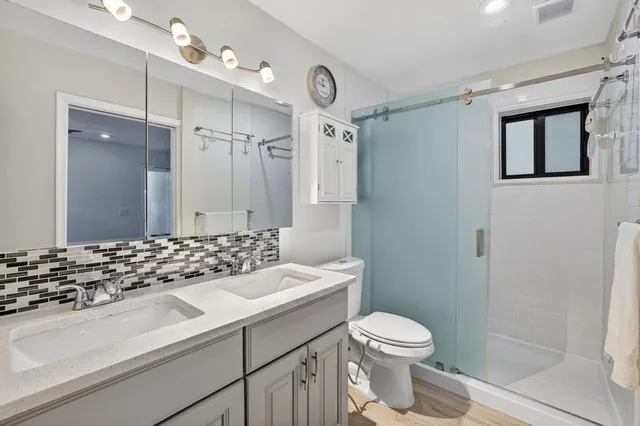 a bathroom with a sink a toilet a mirror a vanity and shower