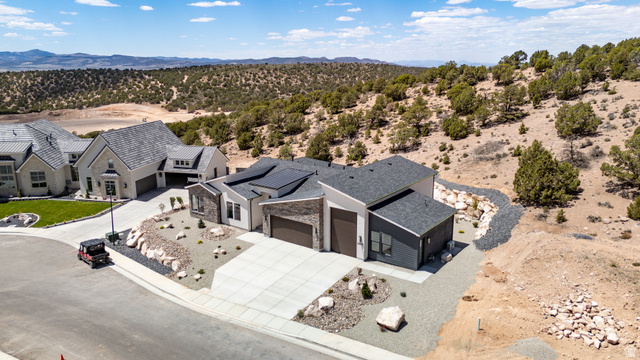 2862 South Mountain Rnch Road Cedar City, UT 84720 - Photo 59 of 64 Modern architectural design featuring a multi-tone exterior, dark shingle roof, integrated solar panels, and an attached two-car garage