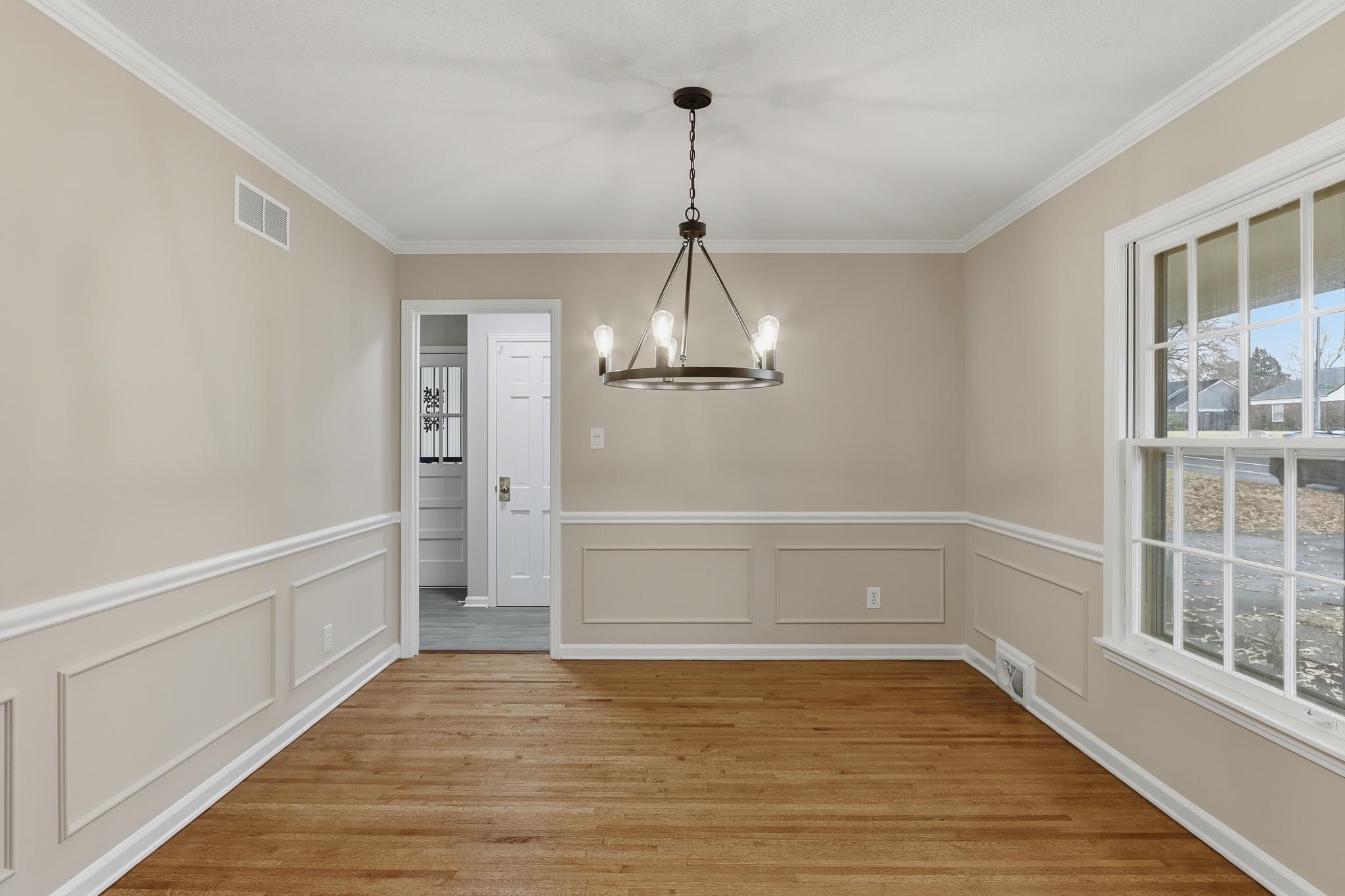 6436 Messick Road Memphis, TN 38119 - Photo 8 of 40 Unfurnished dining area featuring light wood finished floors, ornamental molding, a chandelier, wainscoting, and a decorative wall
