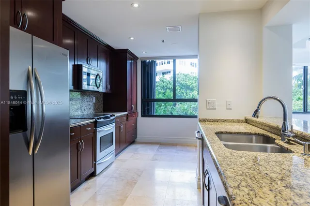 a kitchen with stainless steel appliances granite countertop a sink a stove and a refrigerator