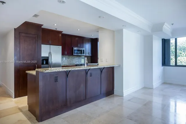 a kitchen with stainless steel appliances granite countertop wooden cabinets a refrigerator and a sink