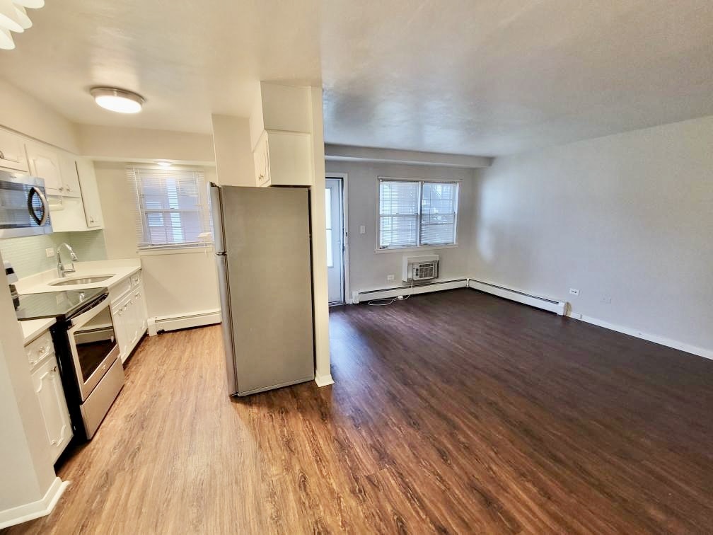 6046 West Pershing Road, Unit 4 Cicero, IL 60804 - Photo 5 of 8 an empty room with wooden floor and a kitchen