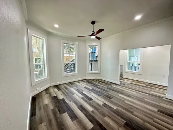 a view of an empty room with window and wooden floor
