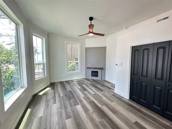 a view of empty room with wooden floor and fan