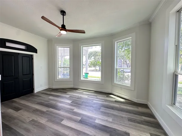 a view of an empty room with a window and wooden floor