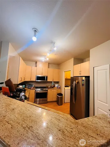 a kitchen with stainless steel appliances kitchen island granite countertop a refrigerator and a stove