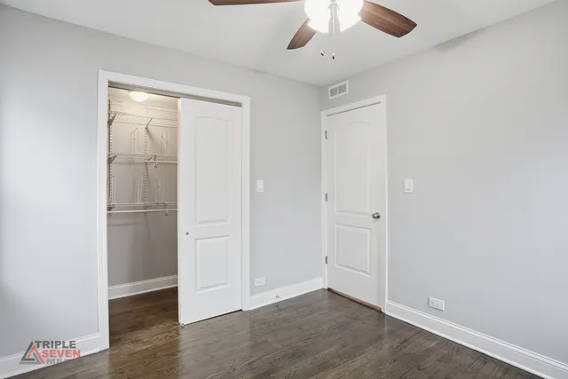 an empty room with wooden floor closet and windows