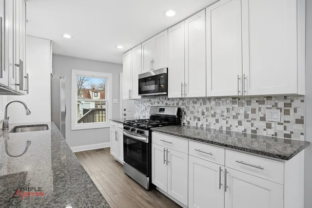 a kitchen with stainless steel appliances granite countertop a stove a sink and a microwave