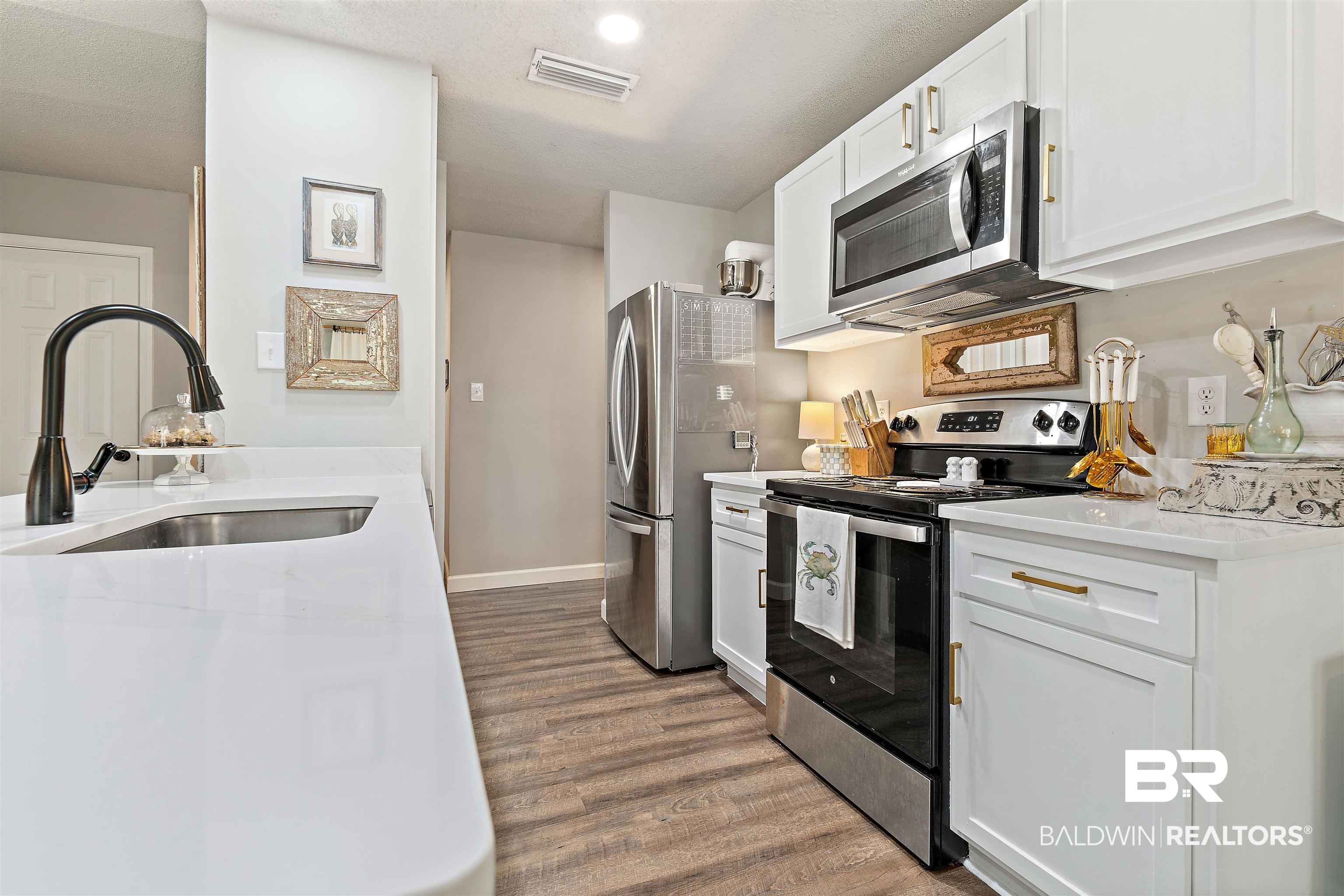 4682 Opal Drive Mobile, AL 36619 - Photo 10 of 27 Kitchen featuring appliances with stainless steel finishes, white cabinetry, sink, and light hardwood / wood-style floors