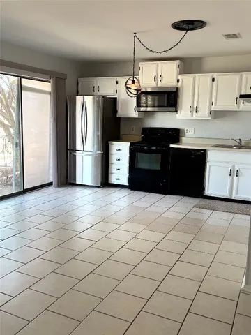 a kitchen with stainless steel appliances granite countertop a refrigerator a sink dishwasher a stove and white cabinets with wooden floor