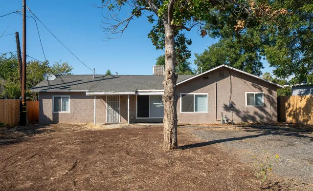 a view of a house with a yard and large tree
