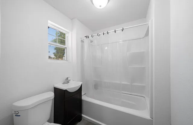 a bathroom with a shower a toilet and a window