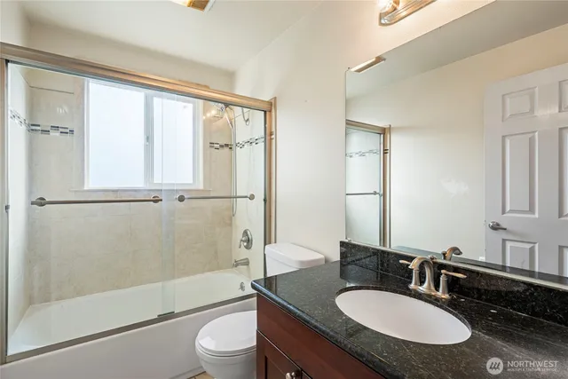 a bathroom with a granite countertop sink toilet a mirror and shower