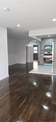 a view of a livingroom with wooden floor and a kitchen