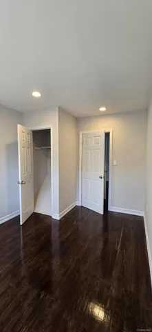 a view of an empty room with wooden floor and closet