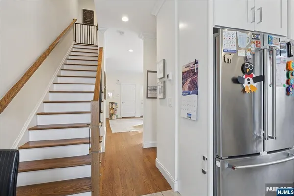 a kitchen with stainless steel appliances granite countertop a stove a sink dishwasher and white cabinets with wooden floor