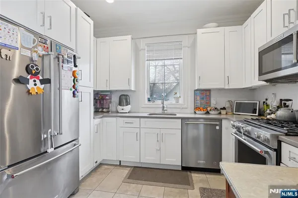 a kitchen with cabinets stainless steel appliances a sink and a window