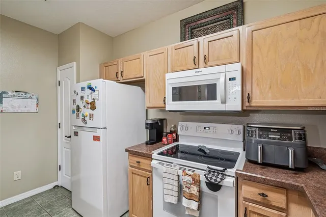 a white kitchen with stainless steel appliances a stove a microwave and a refrigerator
