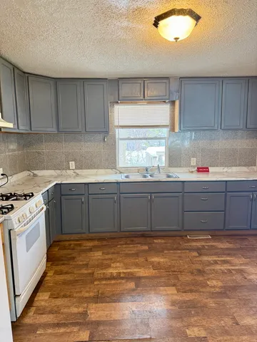 a kitchen with granite countertop a sink stainless steel appliances and cabinets