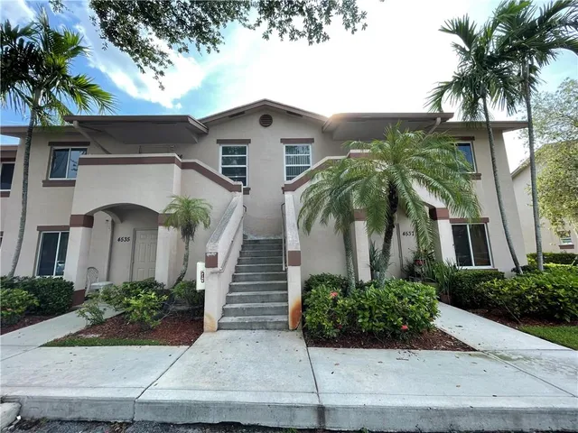 a front view of a house with plants and entryway