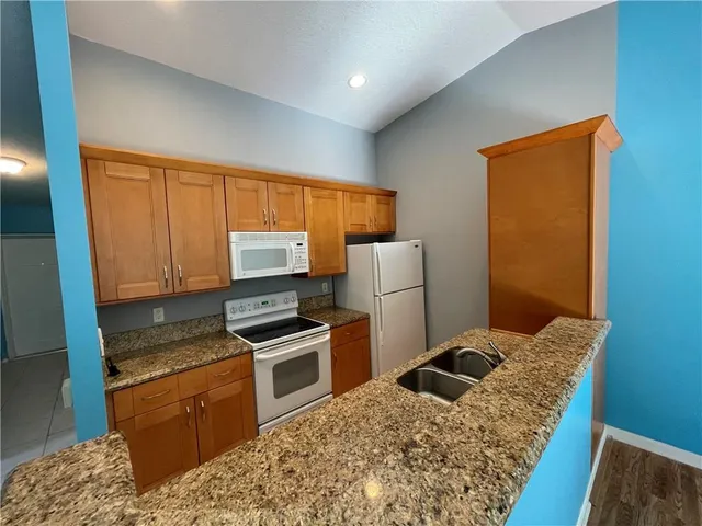 a kitchen with granite countertop a refrigerator stove and oven