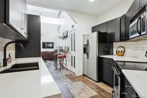 a kitchen with stainless steel appliances kitchen island granite countertop a refrigerator a stove and a sink with wooden cabinets