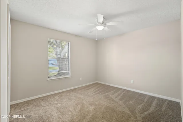 an empty room with windows and fan