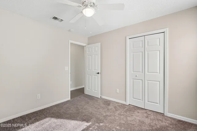 an empty room with a ceiling fan and a window