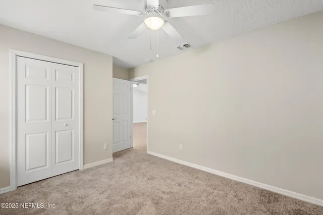 an empty room with a ceiling fan and a window