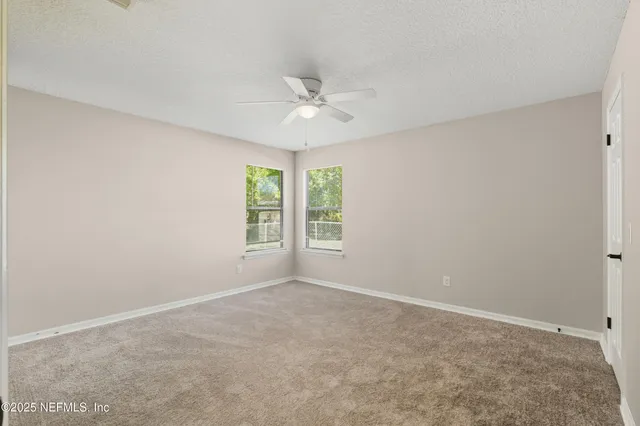 an empty room with windows and fan
