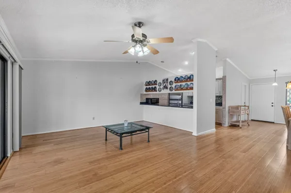 a view of an empty room with wooden floor and a ceiling fan