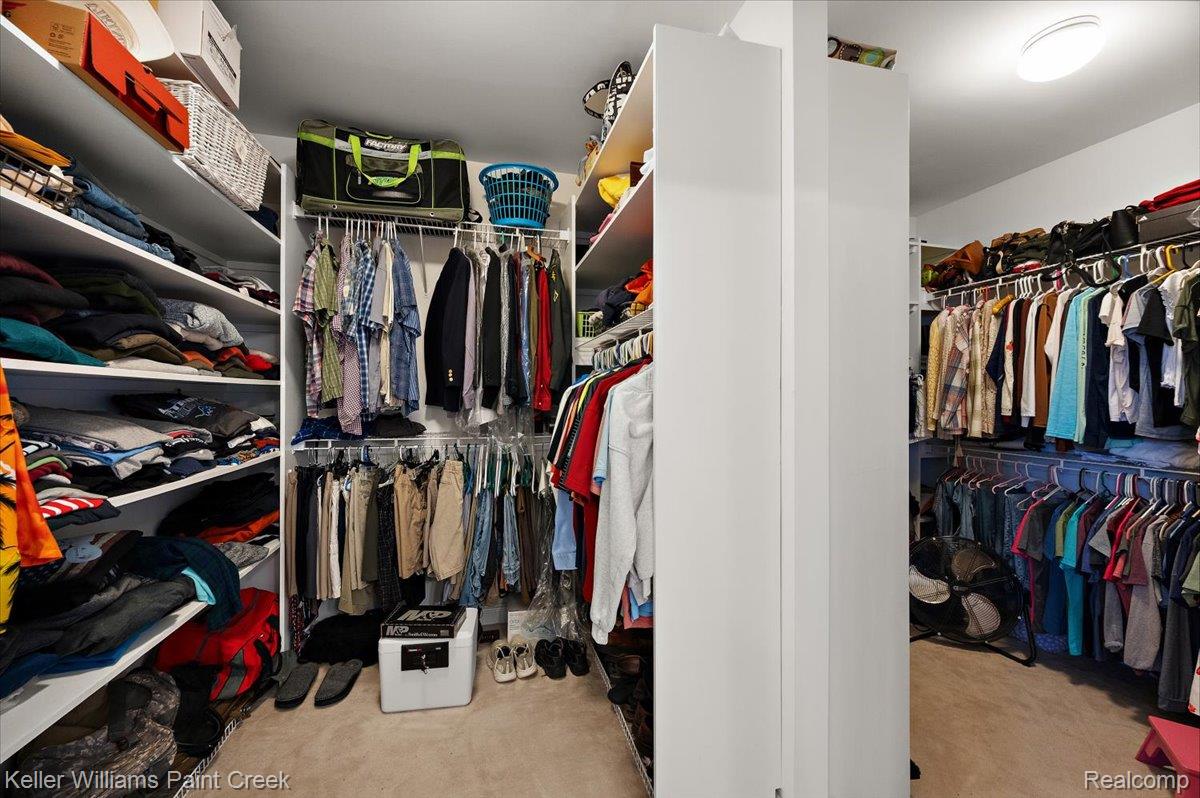 69069 Campground Road Romeo, MI 48065 - Photo 47 of 78 Walk-in closet featuring extensive built-in shelving, multiple hanging rods, and carpet flooring