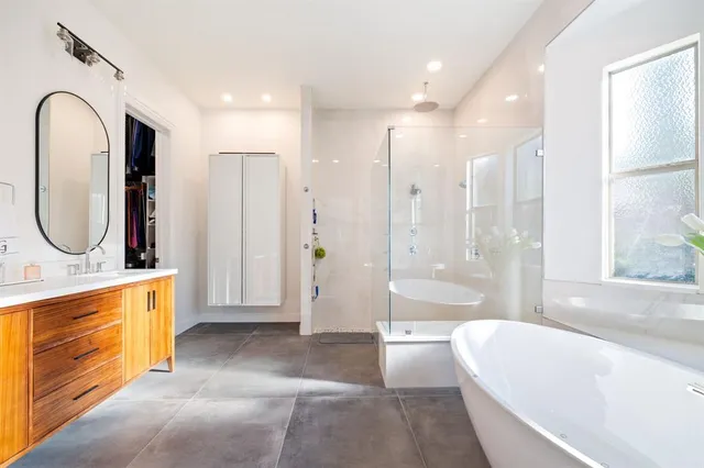a bathroom with a tub a sink and a large mirror