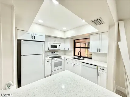 a kitchen with white cabinets and white appliances
