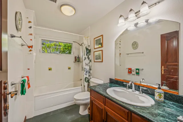 a bathroom with a granite countertop sink a toilet a mirror and shower