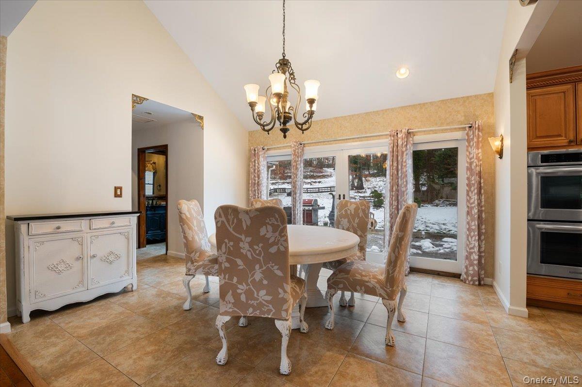 33 Fleets Cove Road Huntington, NY 11743 - Photo 12 of 42 Dining area featuring light tile patterned floors, high vaulted ceiling, a chandelier, and recessed lighting