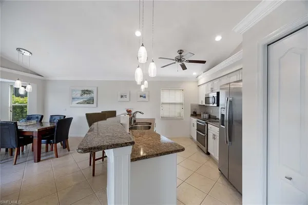 a kitchen with stainless steel appliances kitchen island granite countertop a table chairs and a refrigerator