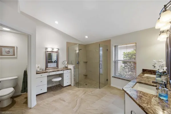 a spacious bathroom with a granite countertop double vanity sink a mirror and a shower