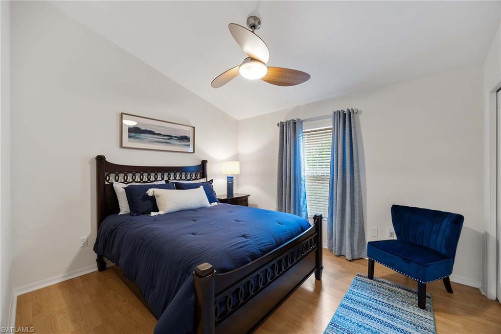 8468 Indian Wells Way Naples, FL 34113 - Photo 22 of 40 a bedroom with a bed wooden floor and window