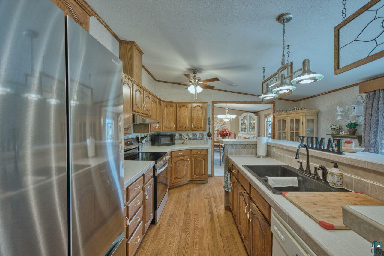 3360 North Leighton Road Hibbing, MN 55746 - Photo 11 of 60 Kitchen featuring stainless steel appliances, decorative light fixtures, light countertops, crown molding, and a chandelier
